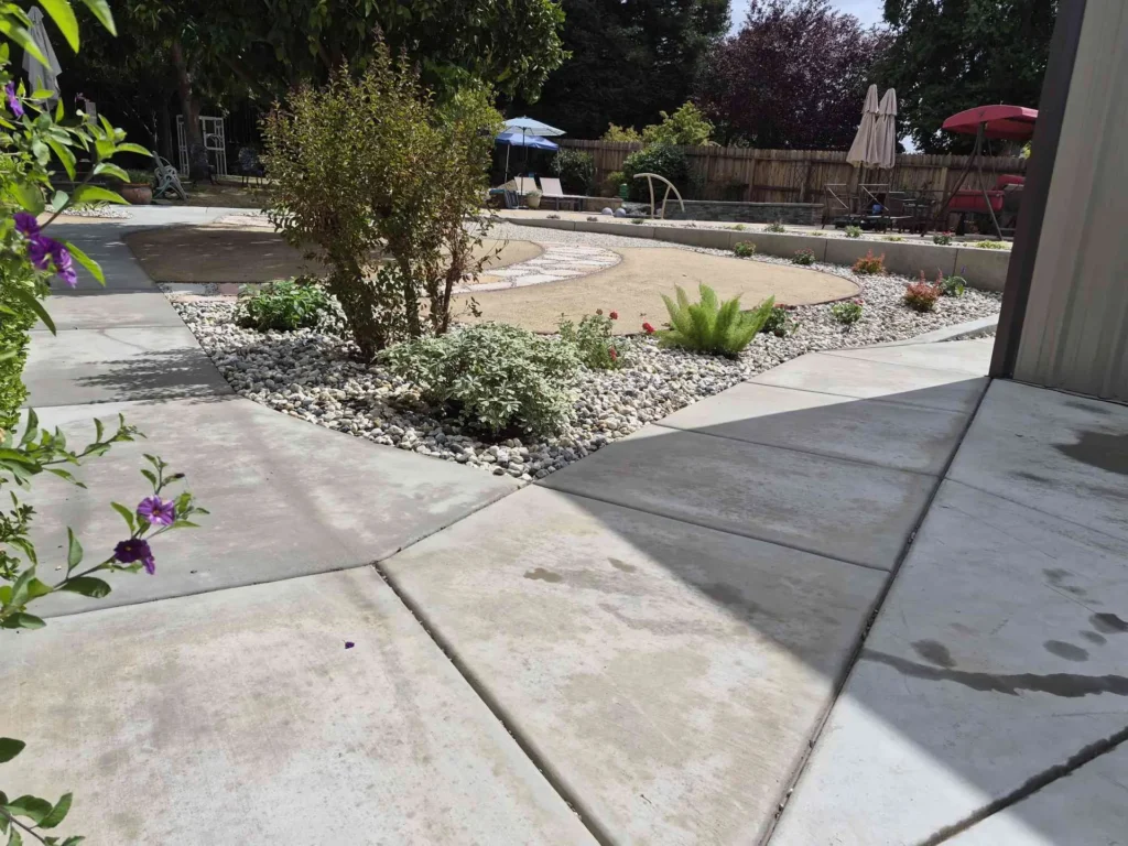 A planted river-rock bed between concrete walkways with a curved path beyond.